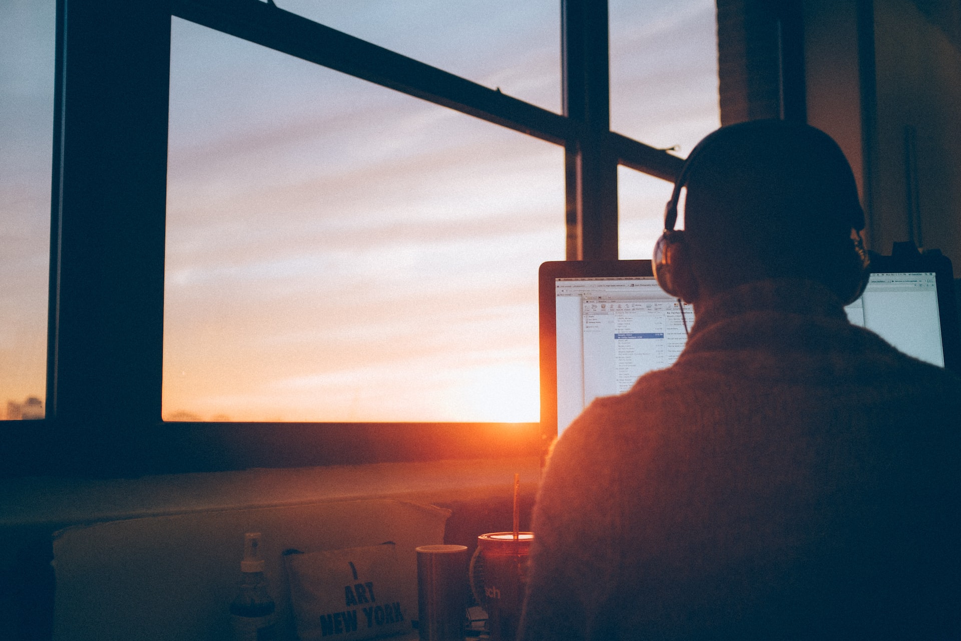 Person using their computer at sunrise while listening to music