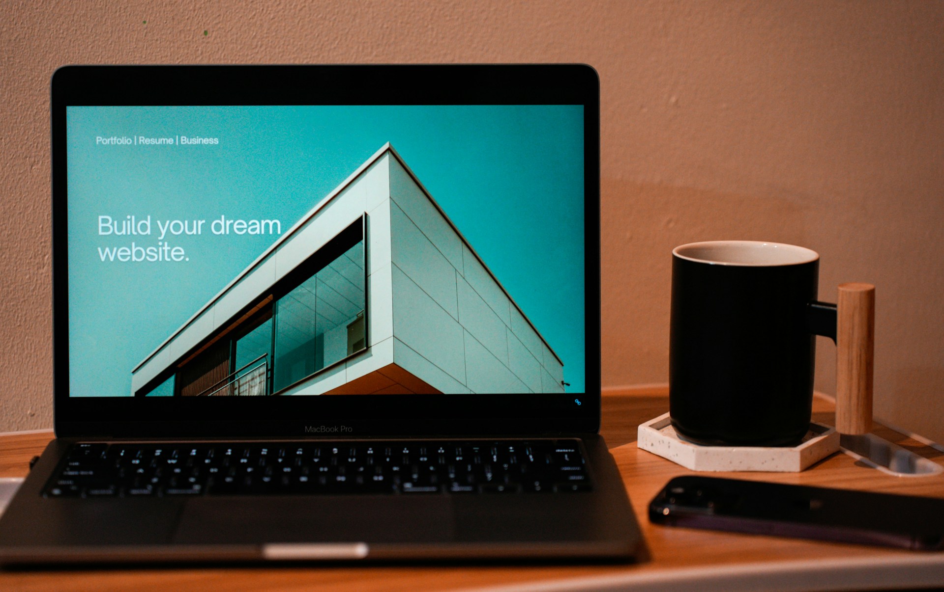 Laptop computer on desk displaying a professional website, with text that reads: Build your Dream website. Photo by Carriza Maiquez on Unsplash